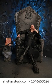 Alternative Fashioned Young Man Sitting On The Satan Throne In Dark Background Alone