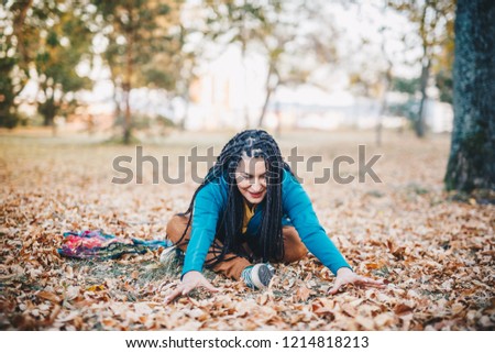 Alternative girl is playing with leaves in park - autumn concept