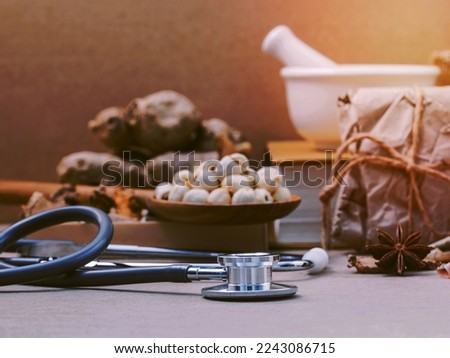 Alternative health care lotus seed in wooden spoon put on dried various Chinese herbs in wooden box and medical textbook with mortar on brown background. Depth of field selective focus on stethoscope.