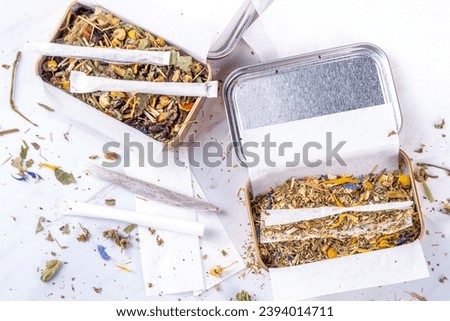 Alternative healthy berbal smoking blend. Handmade craft cigarette, preparation process, with mixture of herbs, leaves and flowers, with boxes, paper, on white background