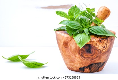 Alternative medicine fresh herbs in the wooden mortar . Food ingredients and seasoning basil, peppermint , dill and green mint  in a wooden mortar set up on white wooden background with copy space