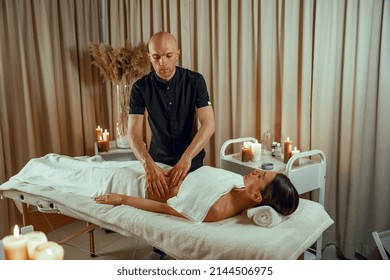 Alternative medicine male therapist doing massage to female client lying on a daybed. Wellness