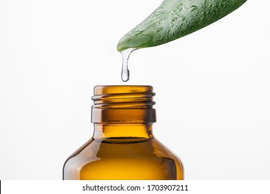 Alternative Medicine And Remedy, Herbal Natural Cosmetics, Aromatherapy And Essential Oil Concept. Water Drop Falling From Leaf Into Bottle Over White Background