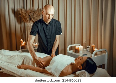 Alternative medicine spa salon therapist doing massage to woman lying on a daybed. Wellness