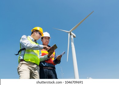 Concepto de desarrollo de proyectos de tecnología de energía alternativa o renovable, ingeniero y arquitecto discuten sobre tableta y portapapeles inalámbricos digitales mientras trabajan en el Generador de energía de turbina eólica a