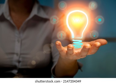 Alternative Renewable Power Sources Concept, Woman Engineer Holding Illuminated Virtual Light Bulb With Green Energy Icons In Hand