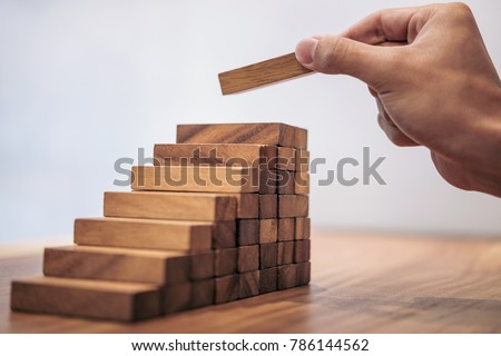Alternative risk concept, plan and strategy in business, Risk To Make Business Growth Concept With Wooden Blocks, hand of man has piling up and stacking a wooden block.