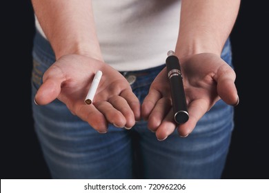 Alternative smoking background. Unrecognizable woman holding vape and tobacco cigarette in hands. Making choice, safe smoking and vaping concept