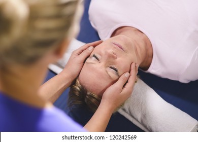 Alternative traditional medicine and massage, young spirit healer doing reiki treatment to old woman. Head and shoulders - Powered by Shutterstock