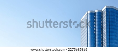 altitudinal building with blue glass facade against a clear, light blue sky. multistory residential building, stylish building, modern style of architecture. Banner, space for text