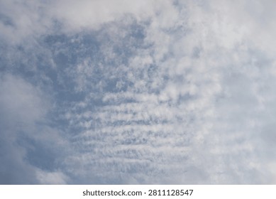 Altocumulus cloud formation in a blue sky. Detailed view of ripples and waves of white clouds on a bright day.