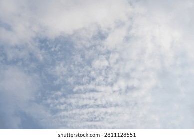 Altocumulus cloud formation in a blue sky. Detailed view of ripples and waves of white clouds on a bright day.