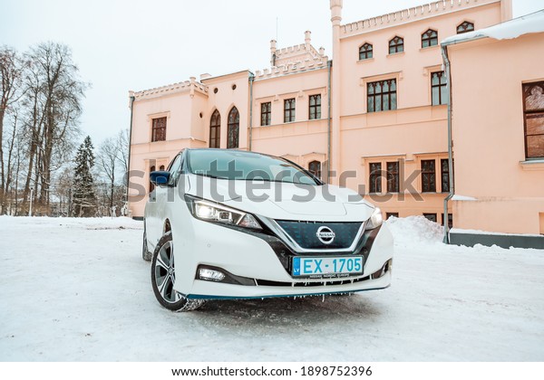 Aluksne, Latvia - 01.12.2021 metallic white\
Nissan Leaf in winter. compact five-door hatchback electric car\
manufactured by Nissan. Zero emission\
car