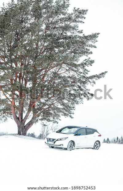 Aluksne, Latvia - 01.12.2021 metallic white Nissan\
Leaf in winter. compact five-door hatchback electric car\
manufactured by Nissan