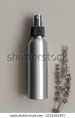 Aluminium cosmetic spray bottle mockup with a lavender on the beige background.