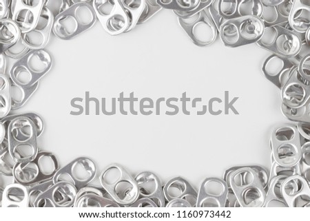 aluminium ring pull opener or ring tabs on white background, free space for text in middle. concept : recycle ringpulls for disable prostheses.