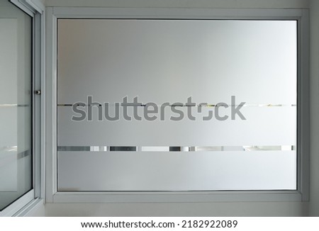 Aluminium sliding window of office. office sliding glass window. Decorative Glass Film on door of office. Closeup Frosted Glass Thick Film for reduced visibility across.
