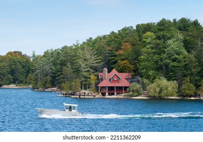 Aluminum Boat Driving Past A Large Upscale Cottage