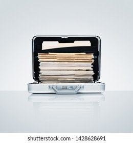 Aluminum briefcase with ambitious stack of files and folders on cool grey aluminum surface with subtle reflection
