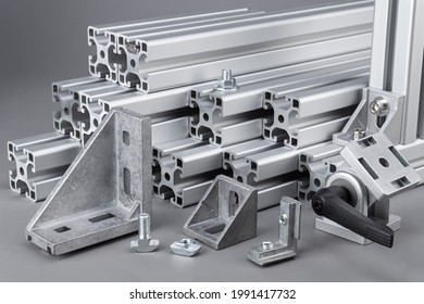 Aluminum exstrusion profile bars with accessories corner angle and screws on gray background. construction industry engineering and material concept.