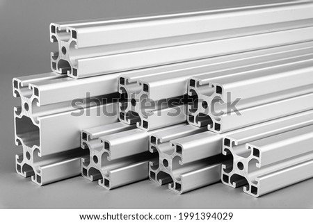 Aluminum exstrusion profile bars on gray background. Metal construction industry engineering and material concept.