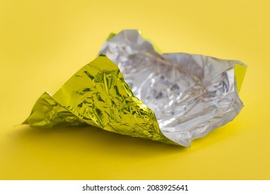 Aluminum Foil Wrap Without Chocolate Candy On A Yellow Background. Texture Of Used Crumpled Aluminium Food Foil.