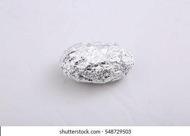 Aluminum Foil Wrapped Baked Potato. Isolated On White With Room For Your Text.