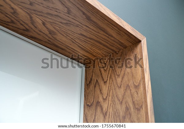 Aluminum frame hidden door with wooden slopes\
and wooden architraves.\
Close-up