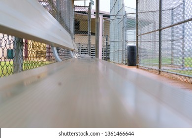 Aluminum Metal Bench In A Little League Baseball Dugout With Distant Focal Point; Protective Chain Link Fence.