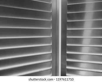 Aluminum Shutters Slightly Opened With Shaft Of Sunlight Across One Section Of The Slats. Also In Monochrome 