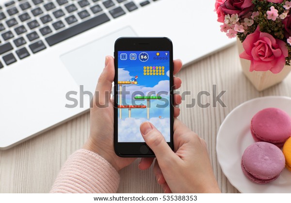Alushta, Russia -\
November 19, 2016: Woman hand holding iPhone 7 Jet Black with game\
Super Mario Run in the screen. Games Super Mario Run was created\
and developed by the\
Nintendo.