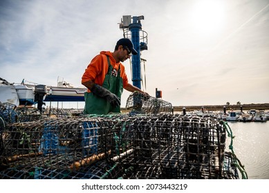 Alvor, Portugal - October 28, 2021: Fisherman puts crab inside octopus traps at the local harbor