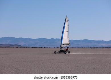 Alvord Desert, Oregon \ USA - 31 August 2019: A man surfing in a  blow cart across playa,  Steens mountains in the background