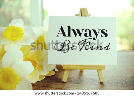Always be kind text message on paper card with wooden easel on wooden table background, inspiration motivation concept