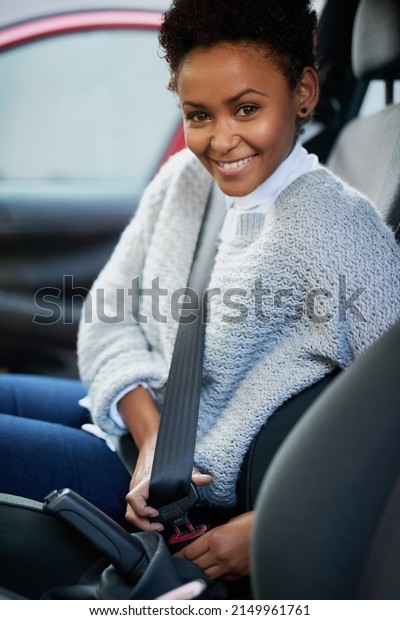 Always buckle up and keep safe.\
Portrait of a young woman fastening her seatbelt in a\
car.