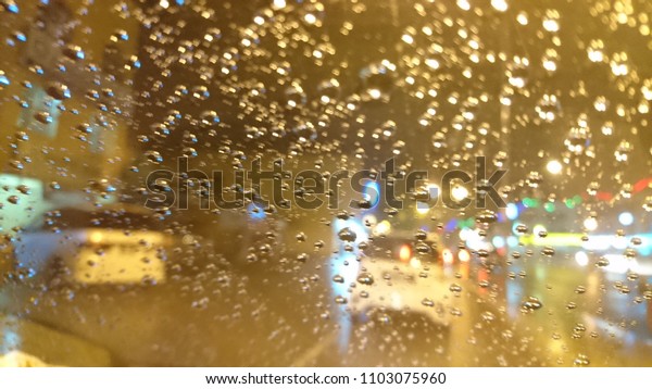 Always drive car with caution when it rains. Rain\
on the city street through a car windshield. Rain drops on window,\
rainy weather