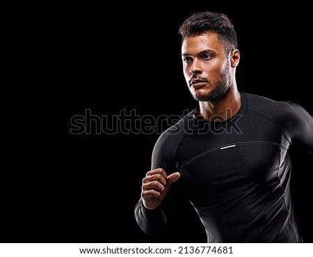 Always give 100 percent. Studio shot of a handsome young man running against a black background.