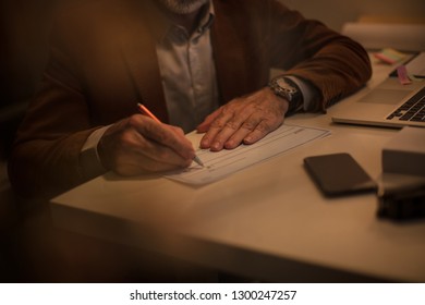 Always Keep The Money In A Safe Place. Senior Man Signing A Check. Close Up. Focus On Hand.