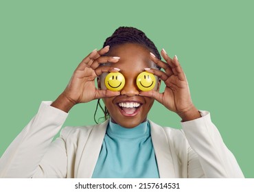 Always keep smiling, look for the good and stay optimistic. Studio shot of a happy lady Positive African American woman covers her eyes holding two smiley faces in hands