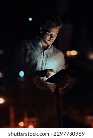 Always in the loop. a young businessman using a digital tablet outside an office at night.
