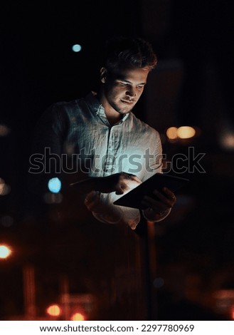 Always in the loop. a young businessman using a digital tablet outside an office at night.
