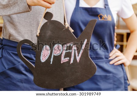 Always open. Two cafeteria workers holding sign open.