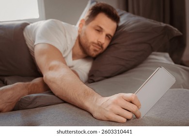 Always In Touch. Man Using Smartphone Waking Up Early In The Morning Lying In Bed At Home. Selective Focus