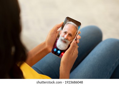 Always In Touch. Over The Shoulder View Of Young Black Woman Making Online Video Call With Senior Bearded Man Using Smartphone, Sitting On Couch At Home. Remote Communication Concept