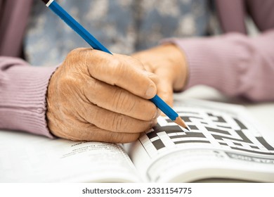 Alzheimer disease AD, Asian elderly woman playing sudoku puzzle game to practice brain training for dementia prevention.