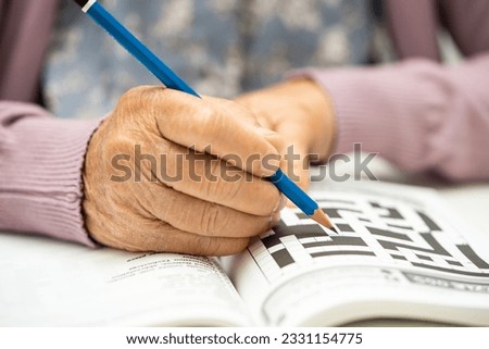 Alzheimer disease AD, Asian elderly woman playing sudoku puzzle game to practice brain training for dementia prevention.