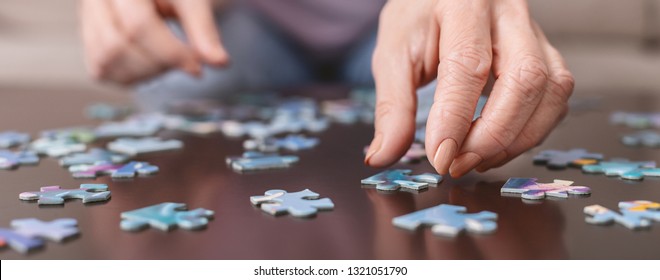 Alzheimer's Disease, Dementia, Memory Loss And Mental Health Concept. Hands Of Old Woman With Jigsaw Puzzle, Panorama, Close Up