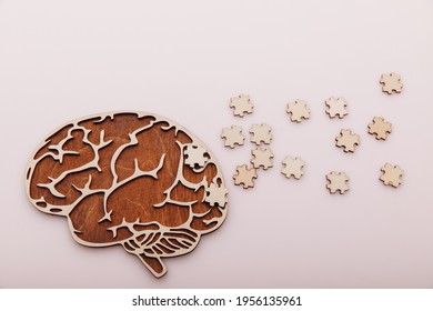 Alzheimer's disease and mental health concept. Brain and wooden puzzle on a pink background