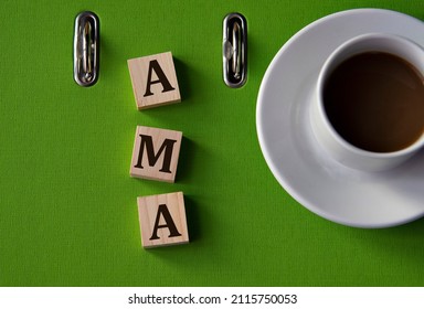 AMA (Ask me anything) - acronym on wooden cubes against the background of a green folder and a cup of coffee.