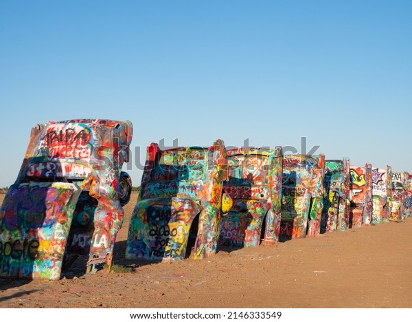 Amarillo, TX - Sep 28, 2020: Cadillacs painted\
with graffiti and partially buried in a field on Route 66 near\
Amarillo, Texas. Public art installation is called Cadillac Ranch.\
Image has copy space.